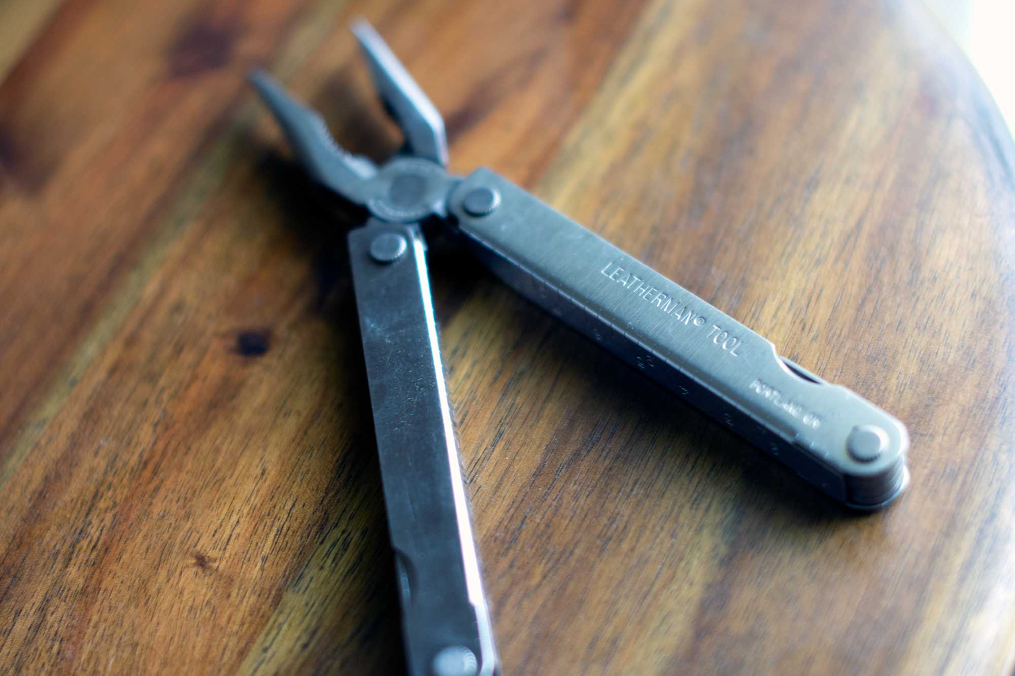 A silver multitool with the words Leatherman tool and Portland, Oregon engraved on it, with needle nose pliers extended