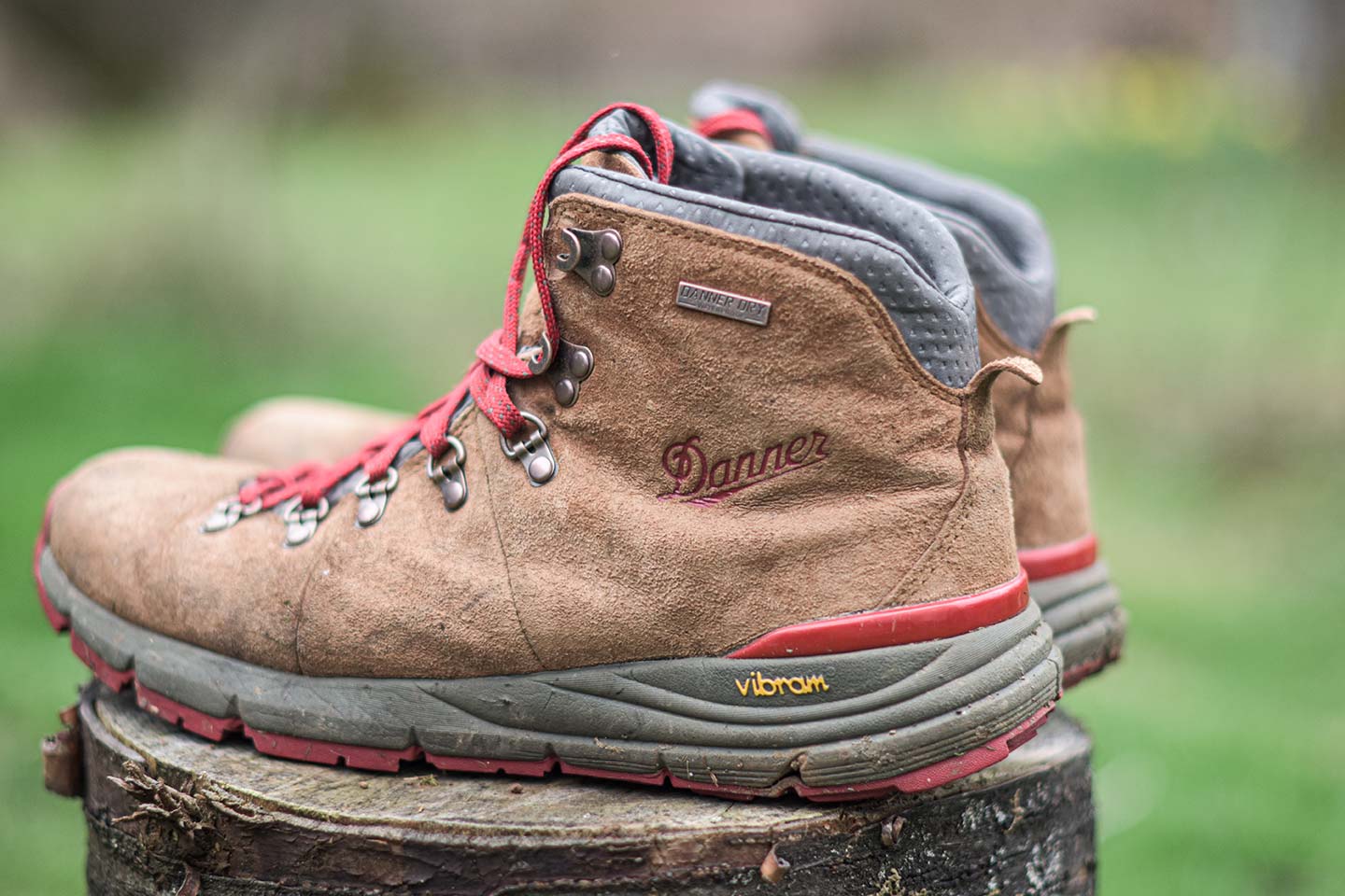 Brown boots with red laces with Danner on the side, a gray midsole, and red outer sole