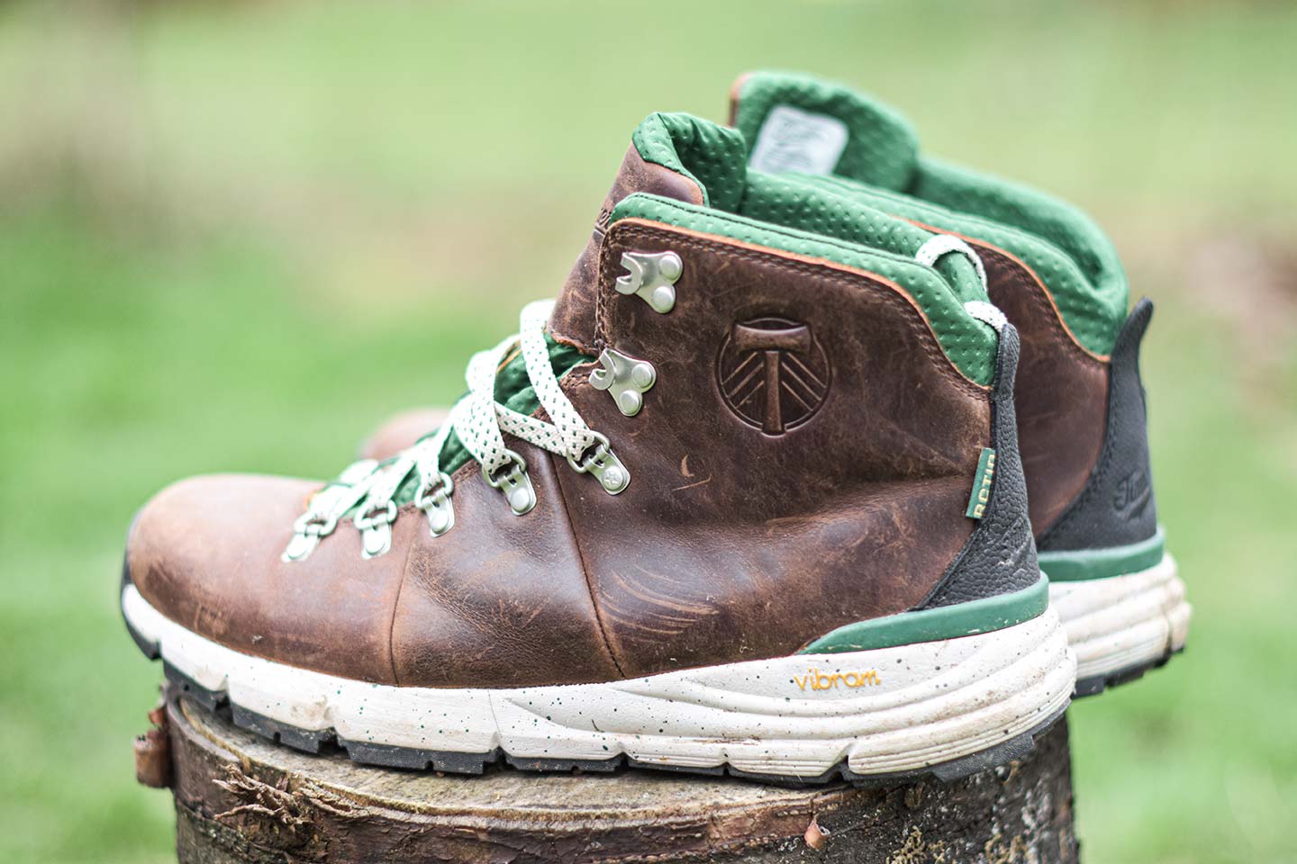 Dark brown boots with the Portland Timbers logo on the side and green laces with a white sole