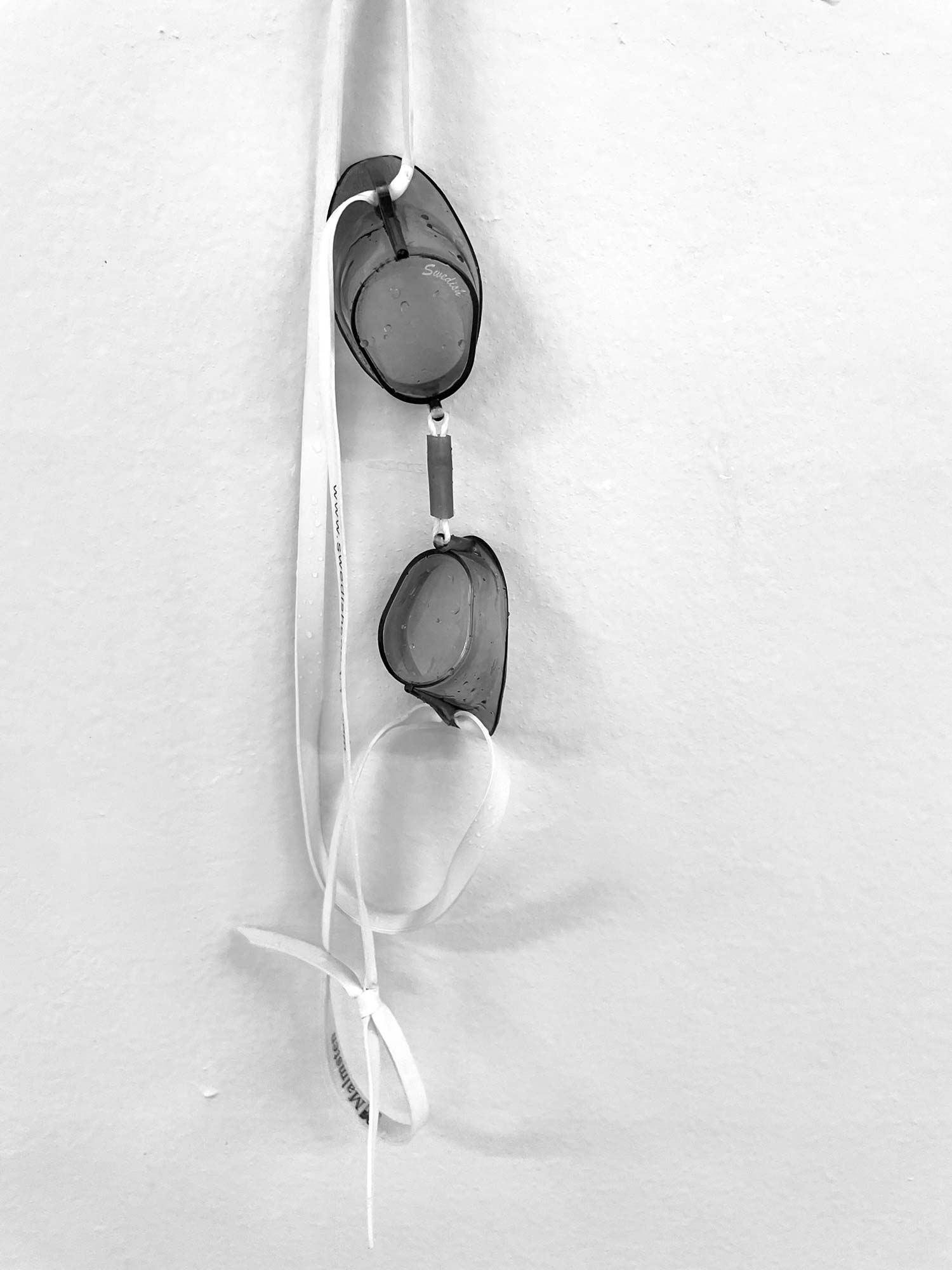 A set of Swedish goggles hanging from a hook on a wall