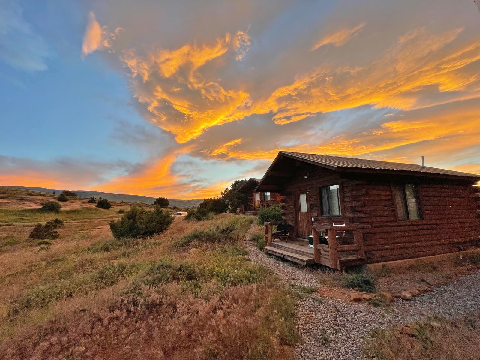 A small log cabin with illuminated orange clouds at sunset overhead