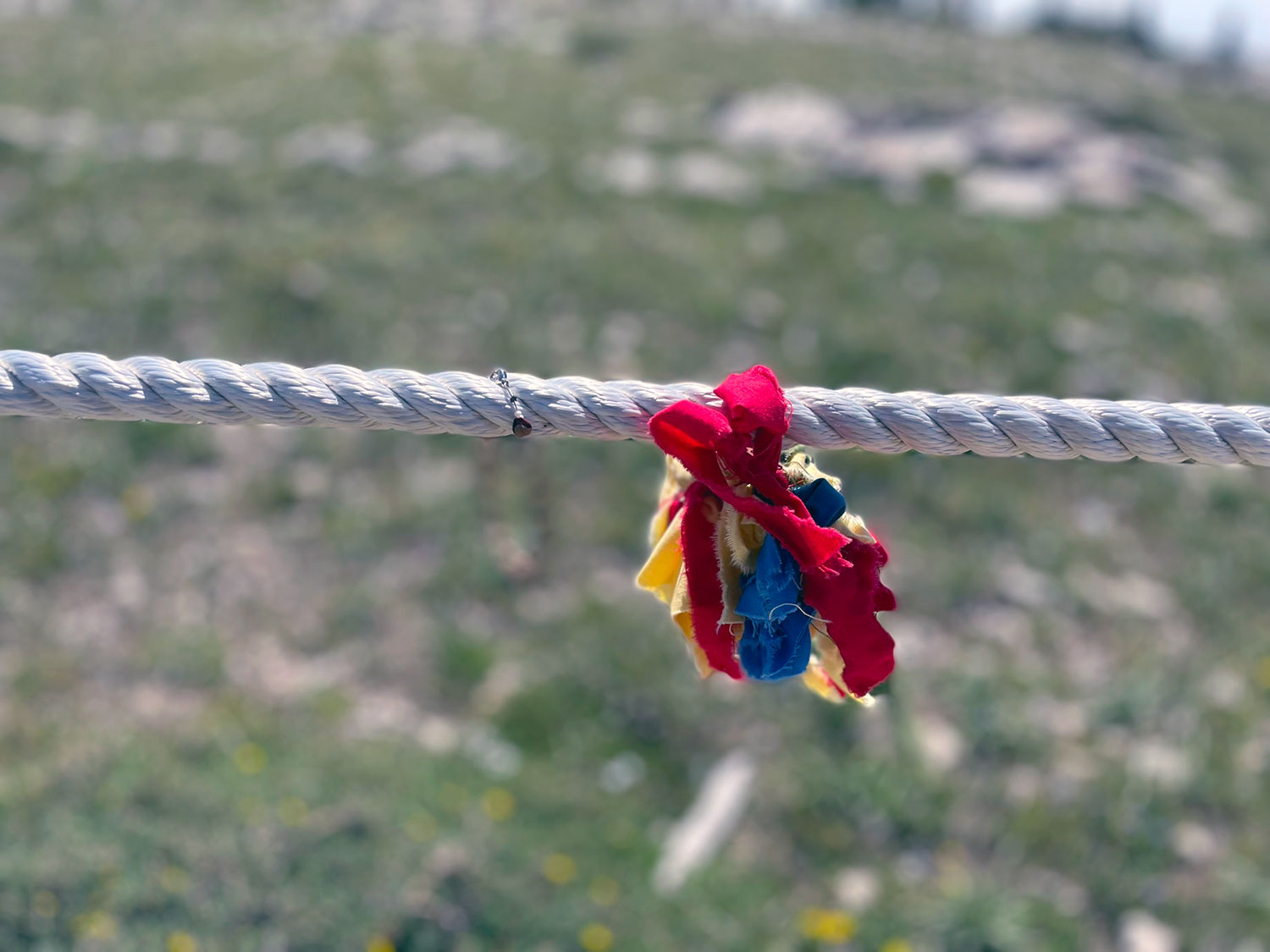 A rope with a bundle of red, yellow, and blue ribbon tied to it