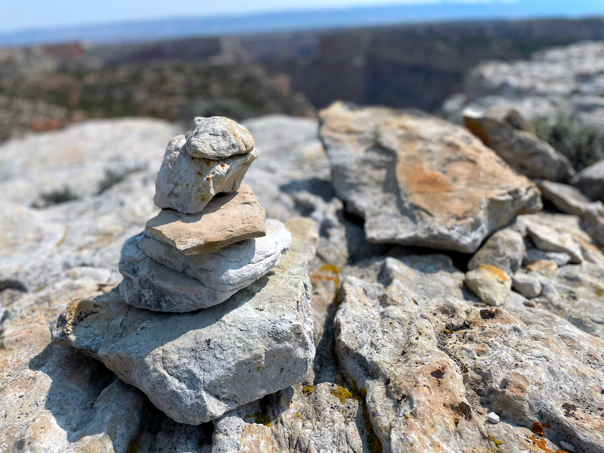 A rock cairn of light-colored rock sits atop a light-colored rock slab