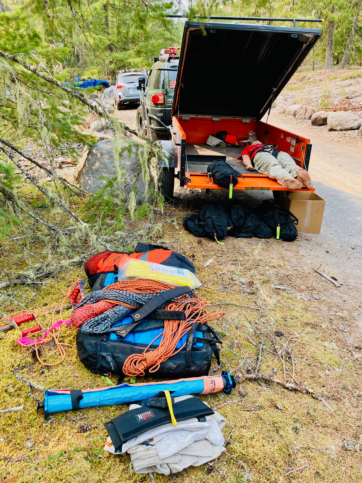Ropes and other gear spread out on the ground behind a search and rescue vehicle with trailer