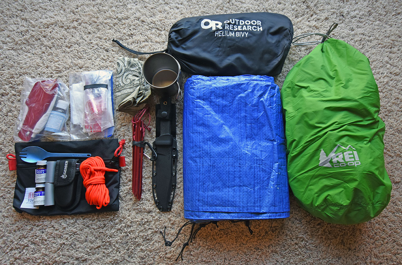 Tarp, bivy, titanium cup, bag of clothing, paracord, spork, water tablets, knife, multi tool, toilet paper, trowel, and tent stakes